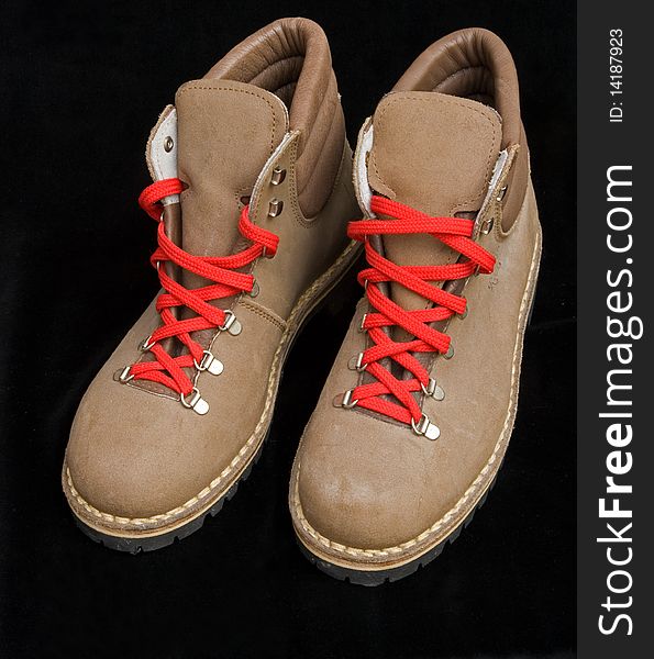 A macro image of new hiking boots with red laces isolated on a dark background. A macro image of new hiking boots with red laces isolated on a dark background.