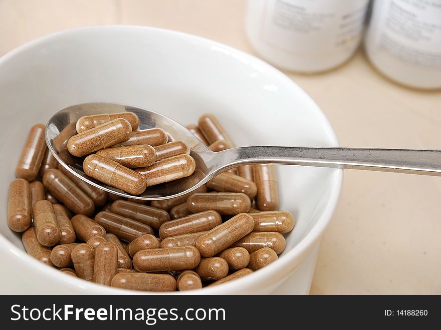 Spoonful of medicine capsules in soup bowl. Signifying drug addiction, healthy eating and lifestyle, dieting and slimming, and healthcare concepts.