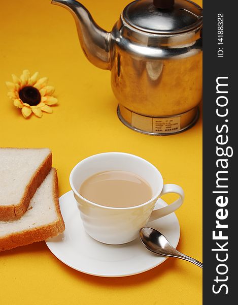 A cup of milky tea with bread and pot