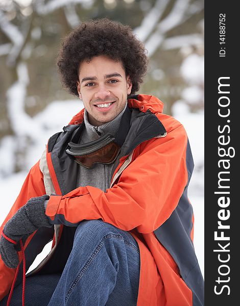 Man Wearing Winter Clothes In Snowy Landscape Looking At Camera