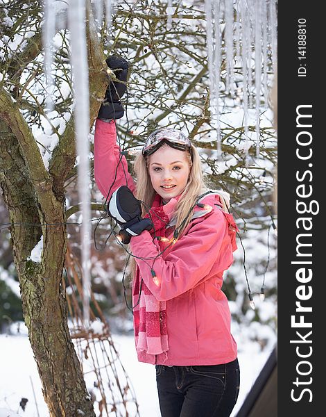 Teenage Girl Hanging Fairy Lights In Tree