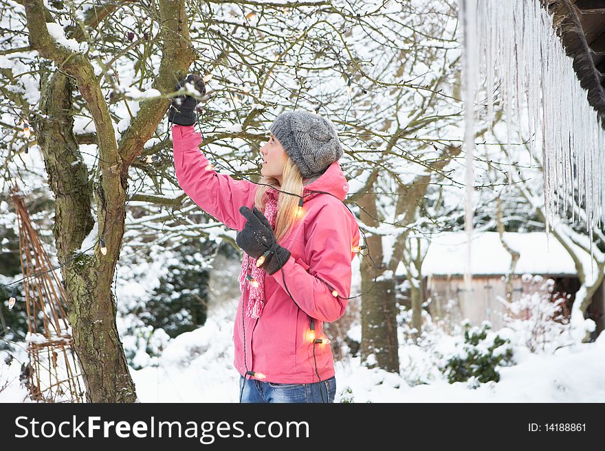 Teenage Girl Hanging Fairy Lights In Tree