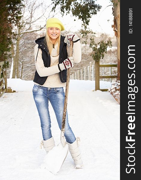 Smiling Teenage Girl Clearing Snow From Drive