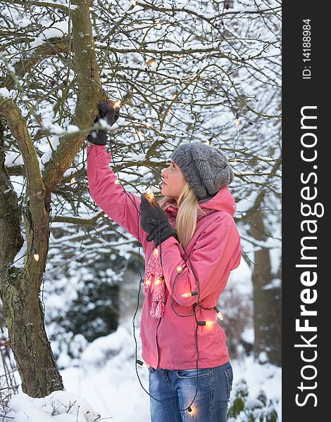 Teenage Girl Hanging Fairy Lights In Tree With Icicles In Foreground