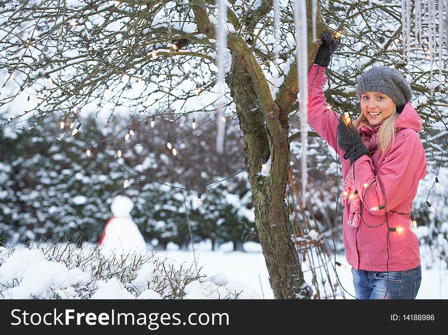 Teenage Girl Hanging Fairy Lights In Tree