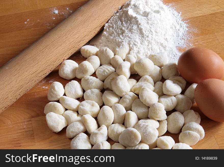 Raw potato gnocchi with eggs, flour and rolling pin on a wooden table. Raw potato gnocchi with eggs, flour and rolling pin on a wooden table