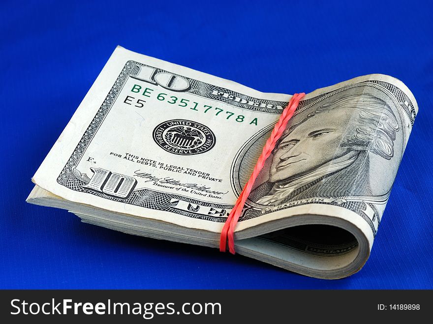 A strap of ten dollar bills isolated on blue