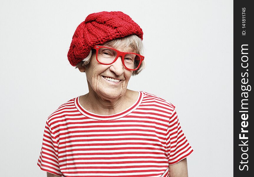 Grey Haired Old Nice Beautiful Woman Wearing Red Hat And Glasses.