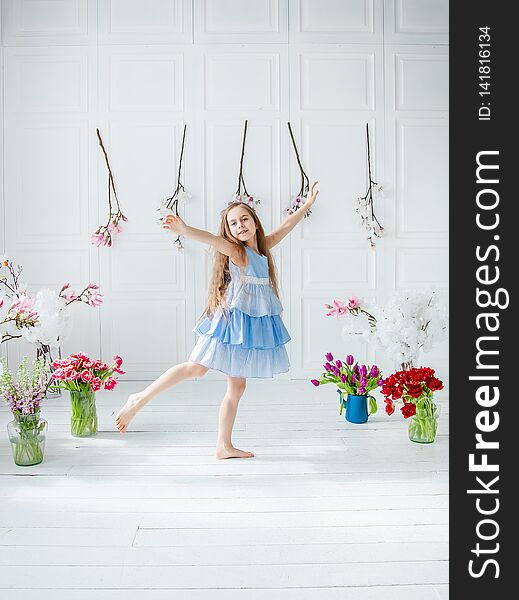 Portrait of a beautiful blue-eyed girl, a little girl among spring flowers in a bright room. Spring break, Mother`s Day, Women`s Day, Easter