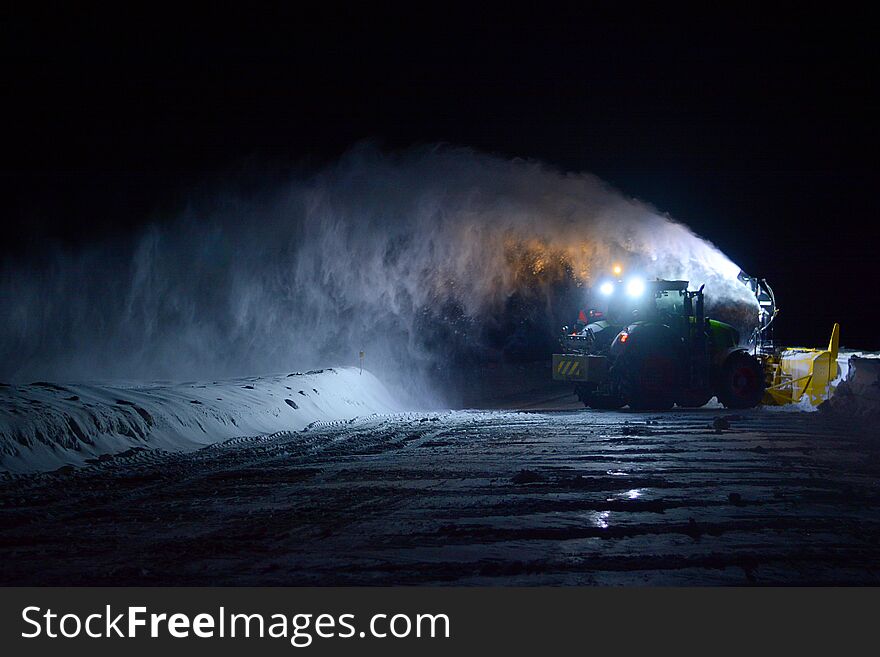 Snow-blower removing snow in the evening on a country road in winter in Canada