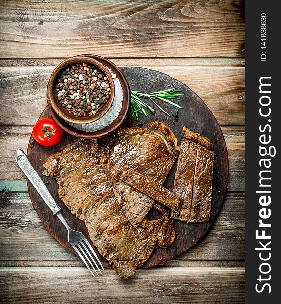 Grilled beef steaks with spices and rosemary. On a wooden background