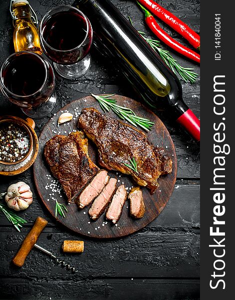 Grilled beef steaks with herbs and red wine. On a black rustic background