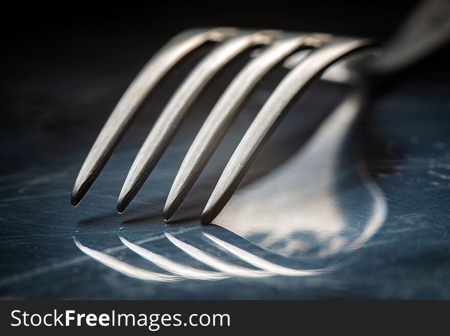 Close-up vintage fork on reflective metal background