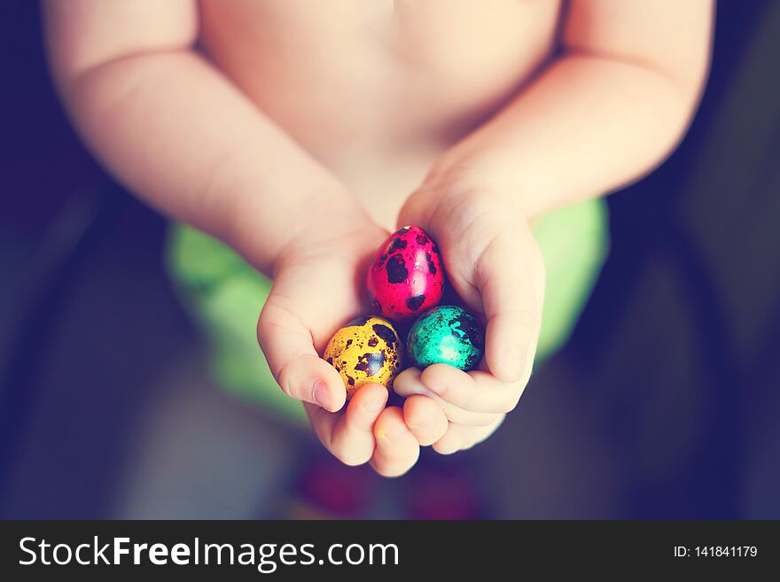 Colorful easter eggs in child hands after egg-hunt.