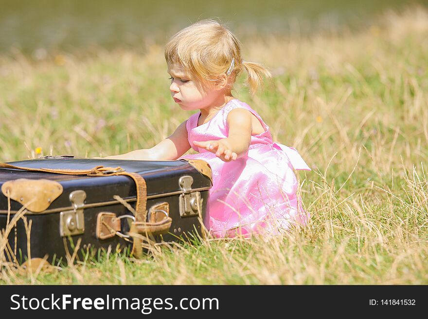 A happy girl with a suitcase outdoors at the park