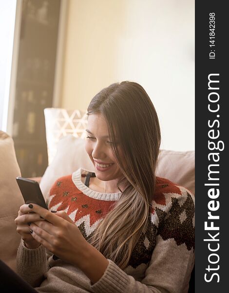 Woman resting on sofa using smartphone. Woman resting on sofa using smartphone