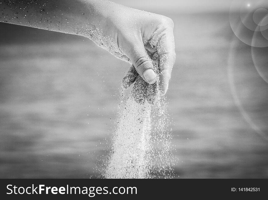 A hands are pouring sand by the sea