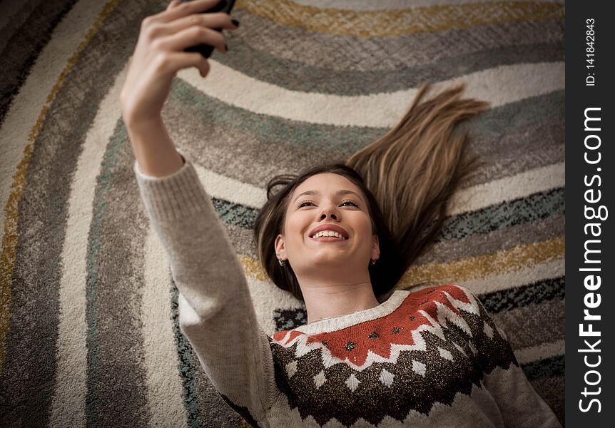 Woman taking a sefie on the floor. Woman taking a sefie on the floor