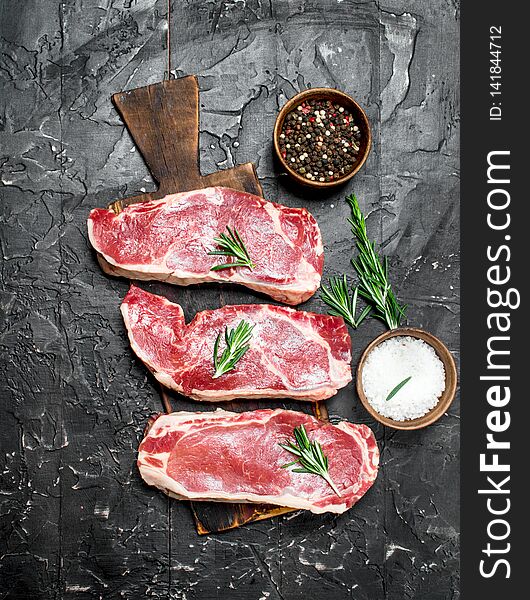 Raw marbled beef steaks with salt and spices. On a black rustic background