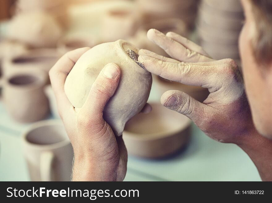 Male potter making ceramic cup, pottery studio background