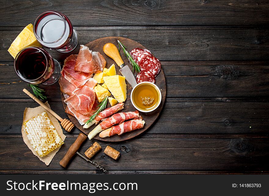 Antipasto background. Various meat and cheese snacks with red wine. On a wooden background. Antipasto background. Various meat and cheese snacks with red wine. On a wooden background