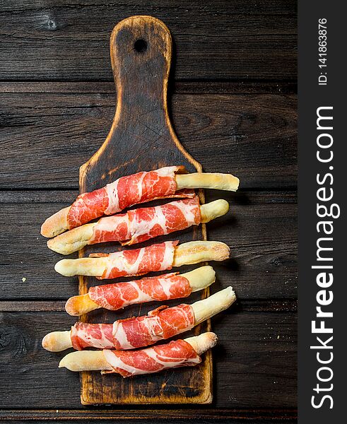 Meat appetizer on bread sticks. On a wooden background