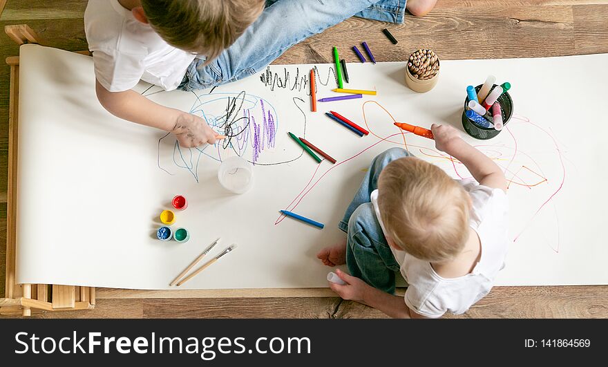 Kids painting with different materials on large canva on the flour