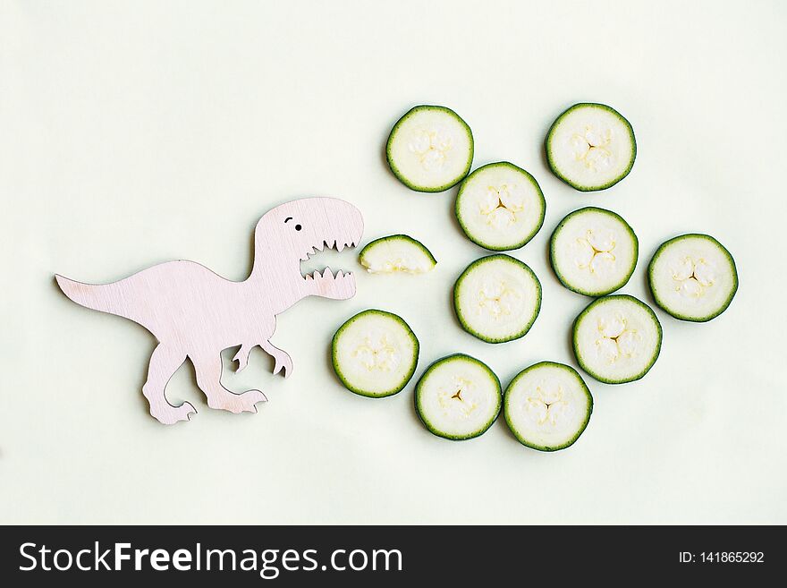 Funny strong dinosaur eating tasty zucchini, healthy vegetables for children, funny meal, flat lay