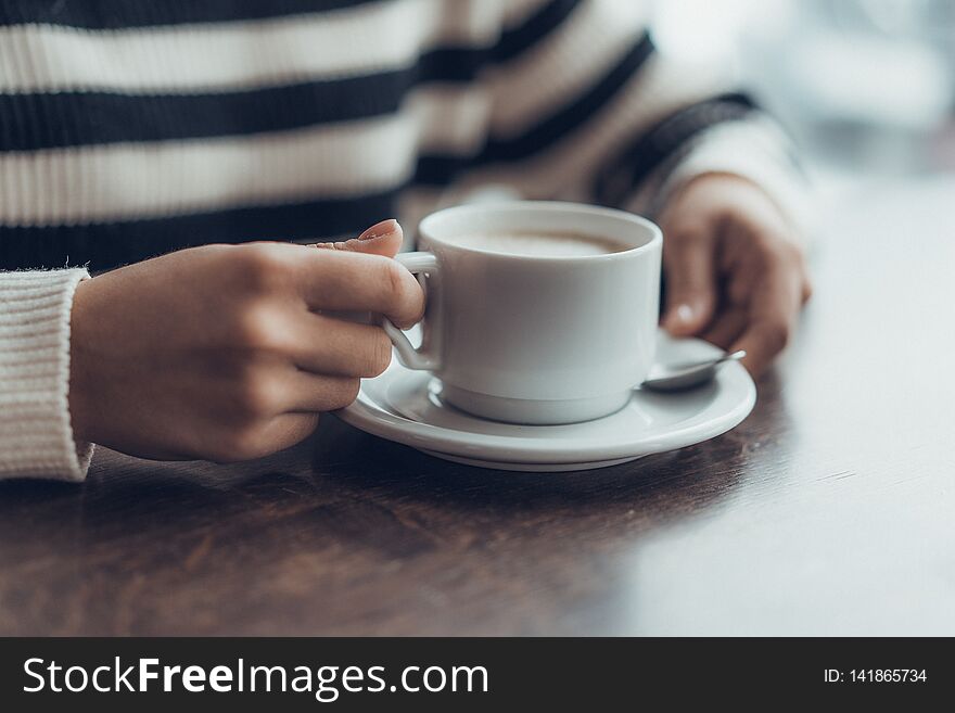 Young girl holding cup of coffe in cafe. waiting something. Horizontal