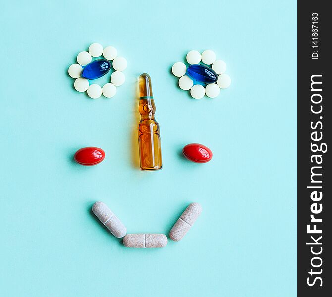 Cute smiling face made of tablets, capsules and an ampule