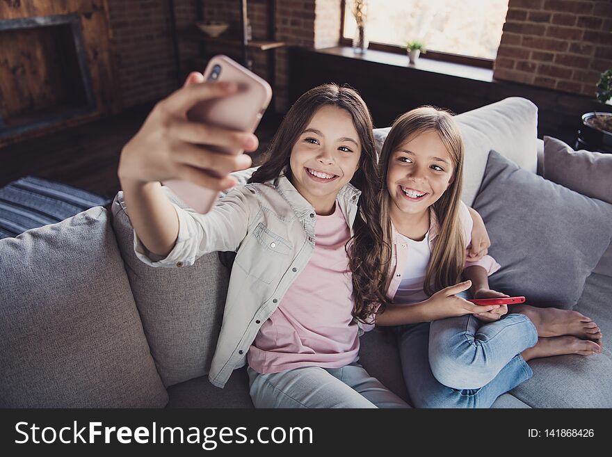 Above high angle view of two nice lovely attractive charming cheerful cheery glad optimistic girls sitting on divan taking making selfie device gadget in house loft industrial interior style.