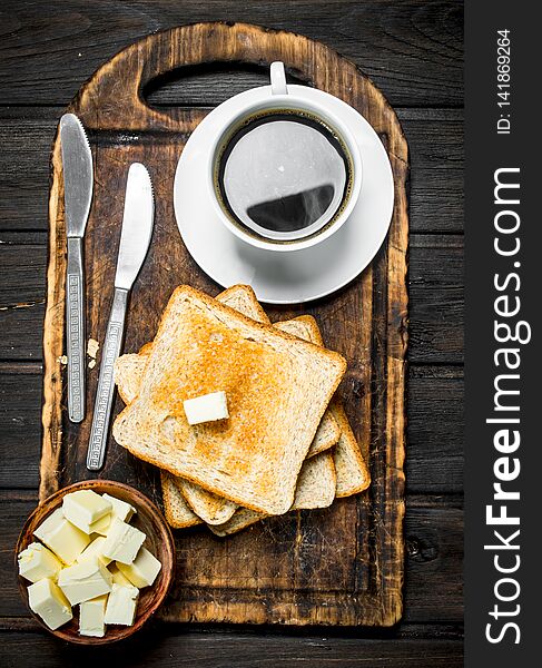 Toasted bread with butter and coffee. On a wooden background