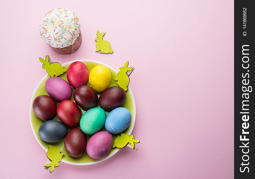 Colorful Easter eggs and Easter bread attributes of Easter celebration. Pink background