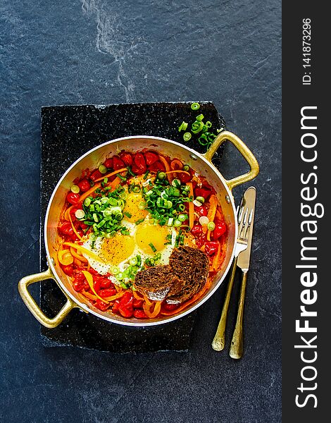 Shakshuka Fried eggs and tomatoes in frying pan on dark background copy space flat lay - Image