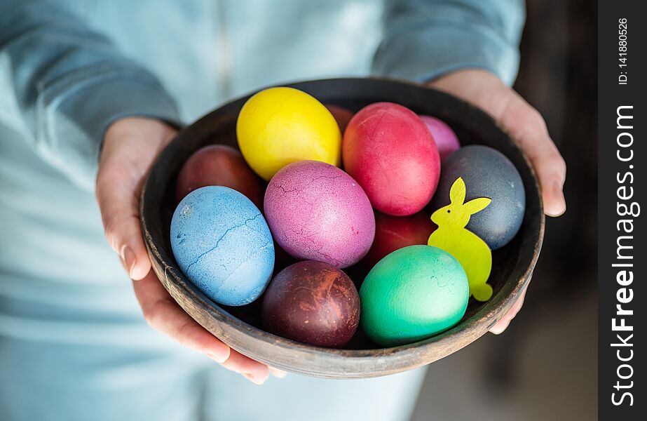 Colorful Easter eggs in bowl in woman`s hands.