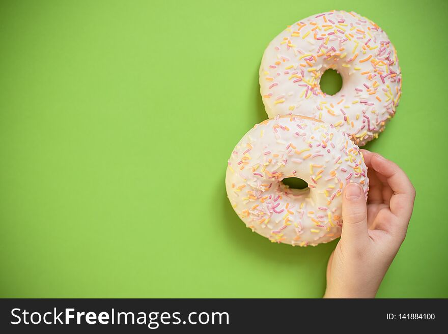 Close up female holds in hand colorful white donut isolated on white background. Proper nutrition or sweets, dessert fast food, dieting morning concept. Copy space for advertisement. Advertising area. Close up female holds in hand colorful white donut isolated on white background. Proper nutrition or sweets, dessert fast food, dieting morning concept. Copy space for advertisement. Advertising area