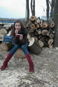 Girl Sitting On Logs With A Mobile Phone Stock Photo
