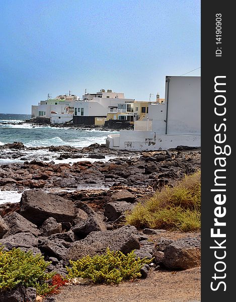 Buildings side of the sea with volcanic rocks and plants