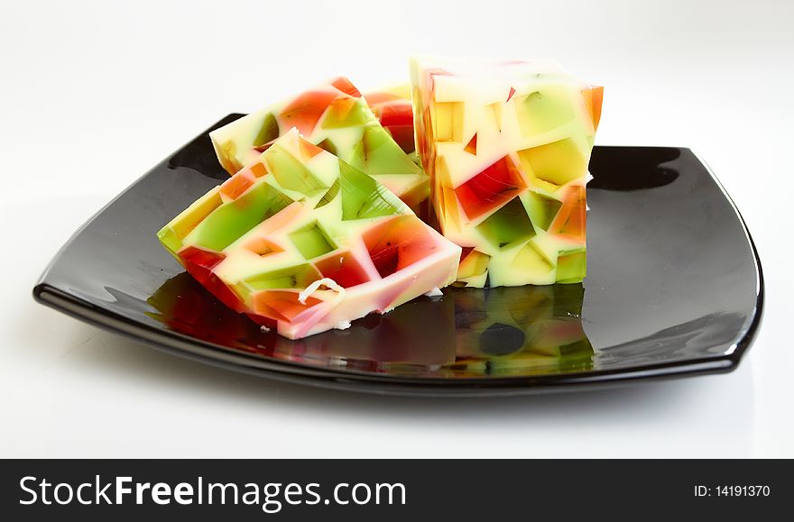 Fruit jelly on black plate on white background