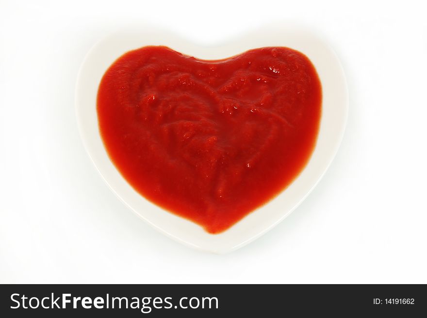 Tomato sauce in the form of heart on a white background