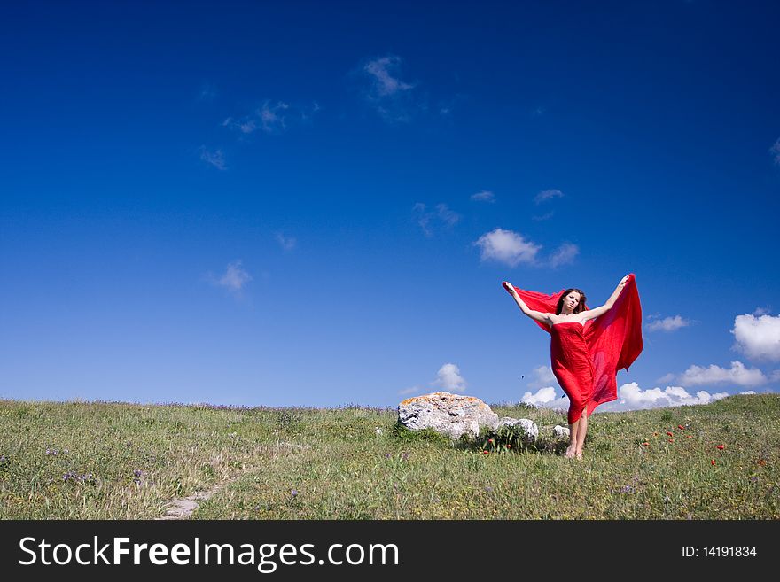 Young beautiful woman in red dress standing on the field. Young beautiful woman in red dress standing on the field