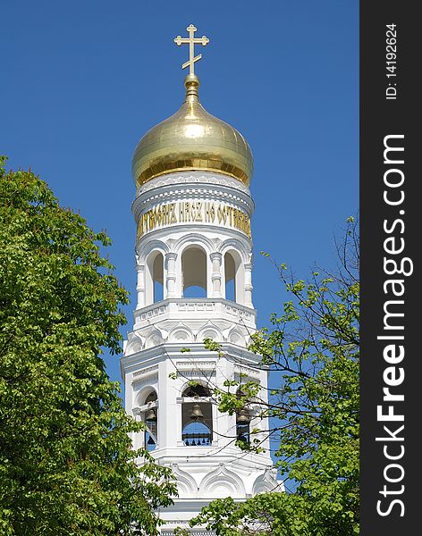 Beautiful russian orthodox cathedral with gold dome and white bell tower on blue sky background. Beautiful russian orthodox cathedral with gold dome and white bell tower on blue sky background.