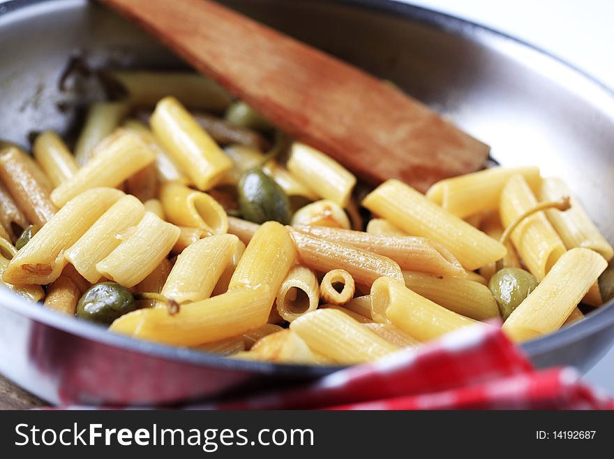 Preparing a dish of penne pasta with pickled capers