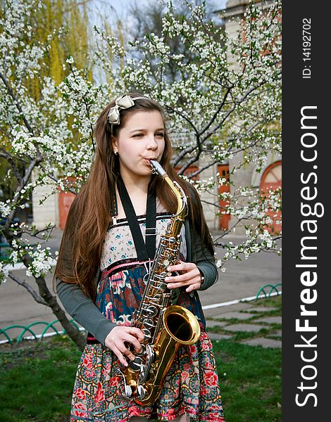 Beautiful smiling girl with saxophone, spring tree. Beautiful smiling girl with saxophone, spring tree