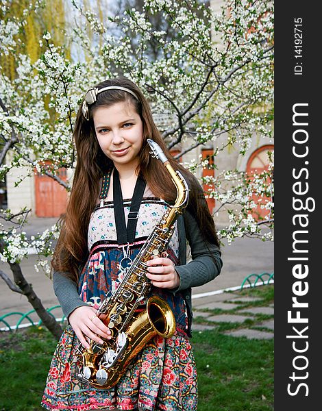 Beautiful smiling girl with saxophone, spring tree. Beautiful smiling girl with saxophone, spring tree
