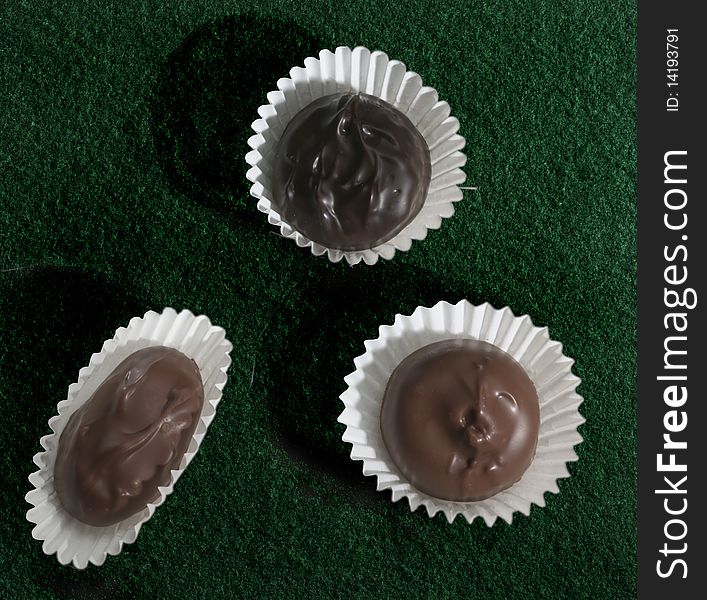 Three paper wrapped chocolate candies on golfing green. Three paper wrapped chocolate candies on golfing green