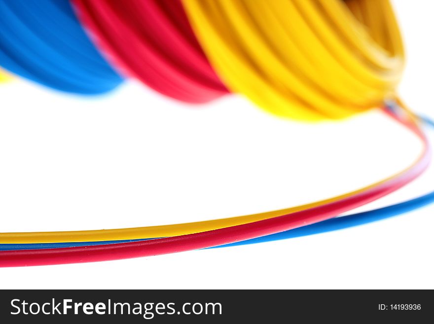 Electric wires of red, yellow and dark blue colour are winded in rings.
