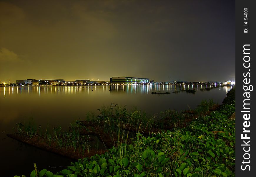 Pandan reservoir with light reflection of yellowish sky at night and greenery foreground. Pandan reservoir with light reflection of yellowish sky at night and greenery foreground