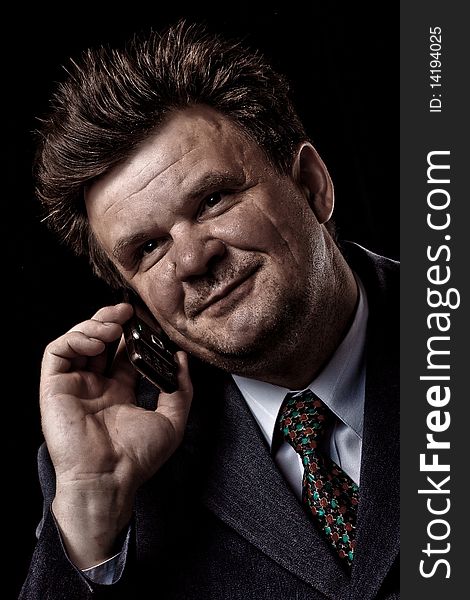 Businessman with mobile phone speaking on black background