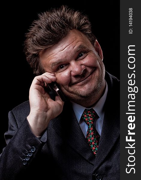 Businessman with mobile phone speaking on black background